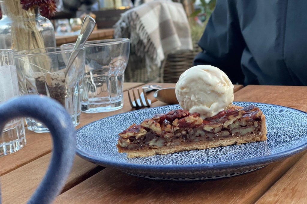 A warm pecan pie with a scoop of honeycomb ice cream on top.
