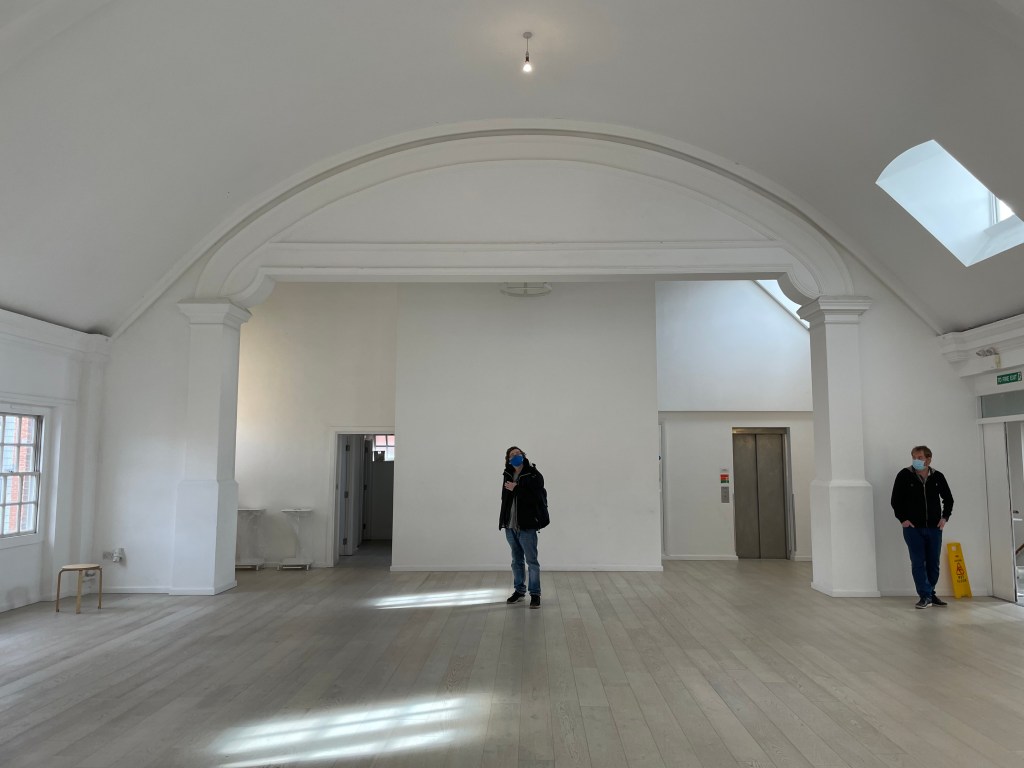 The view of the Old Parish Hall space from the back of the room. Mike stands in the middle as a reference. The venue manager stands on the edge of the room.
