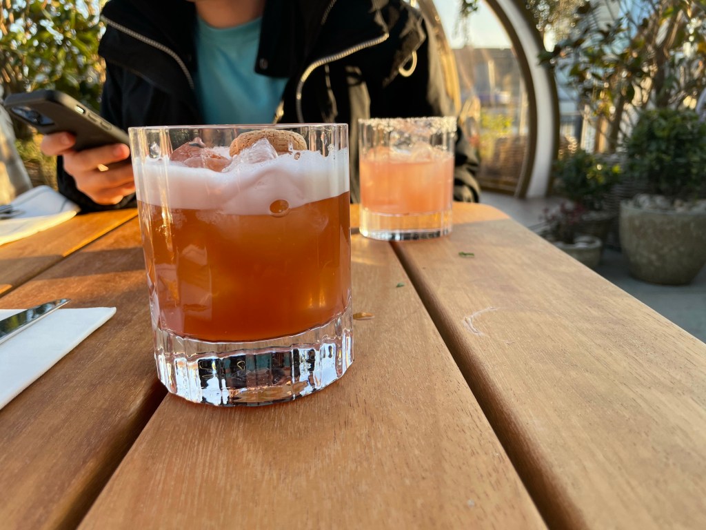 A glass of the Coppa Sour in the foreground, and a glass of the Hibiscus Margarita in the background.